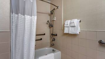 Un baño con bañera, ducha y barras de apoyo.