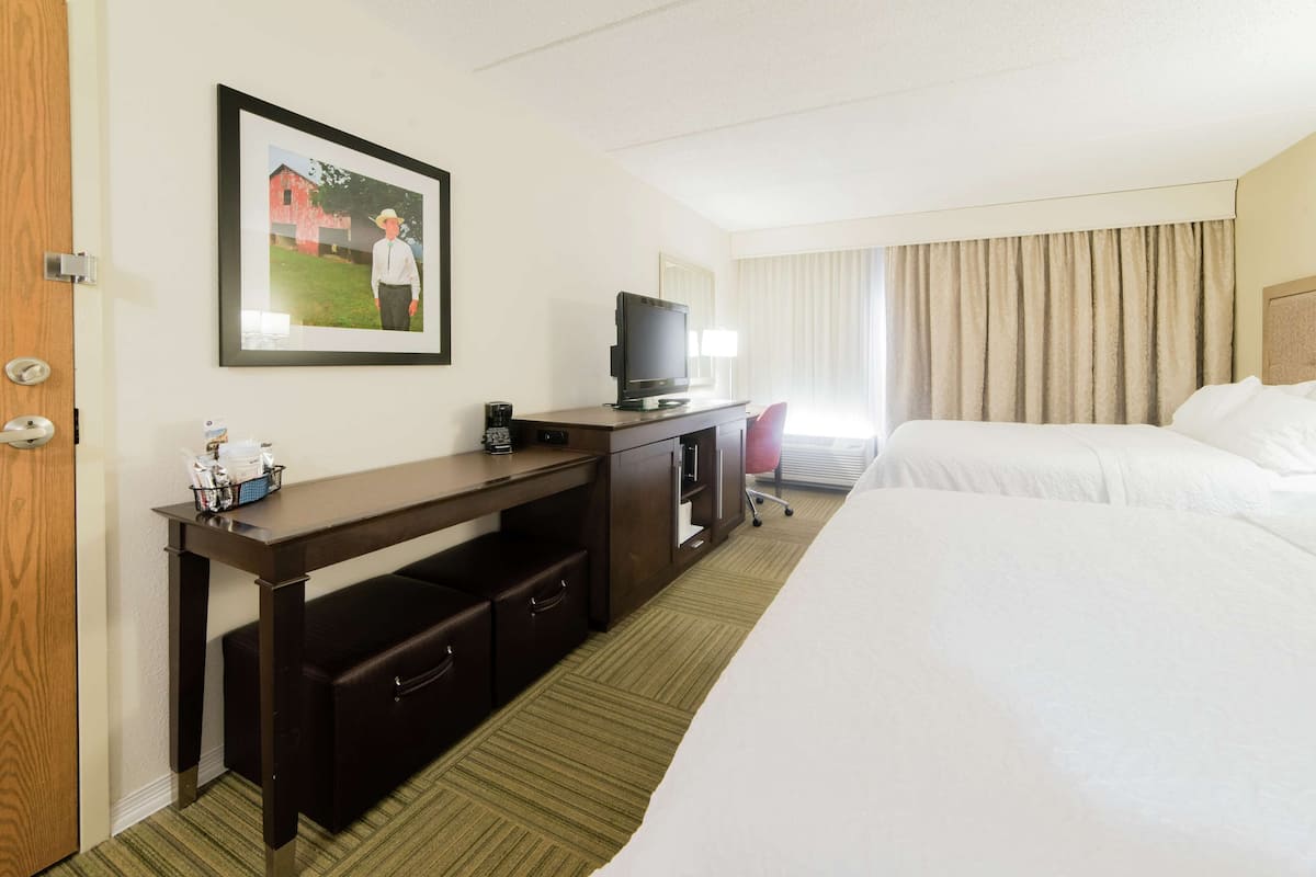A hotel room with a large bed, a desk with a television, and a picture of a man on the wall.