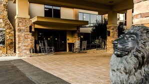 Fachada de piedra, marquesina y estatua de león en la entrada de un edificio.