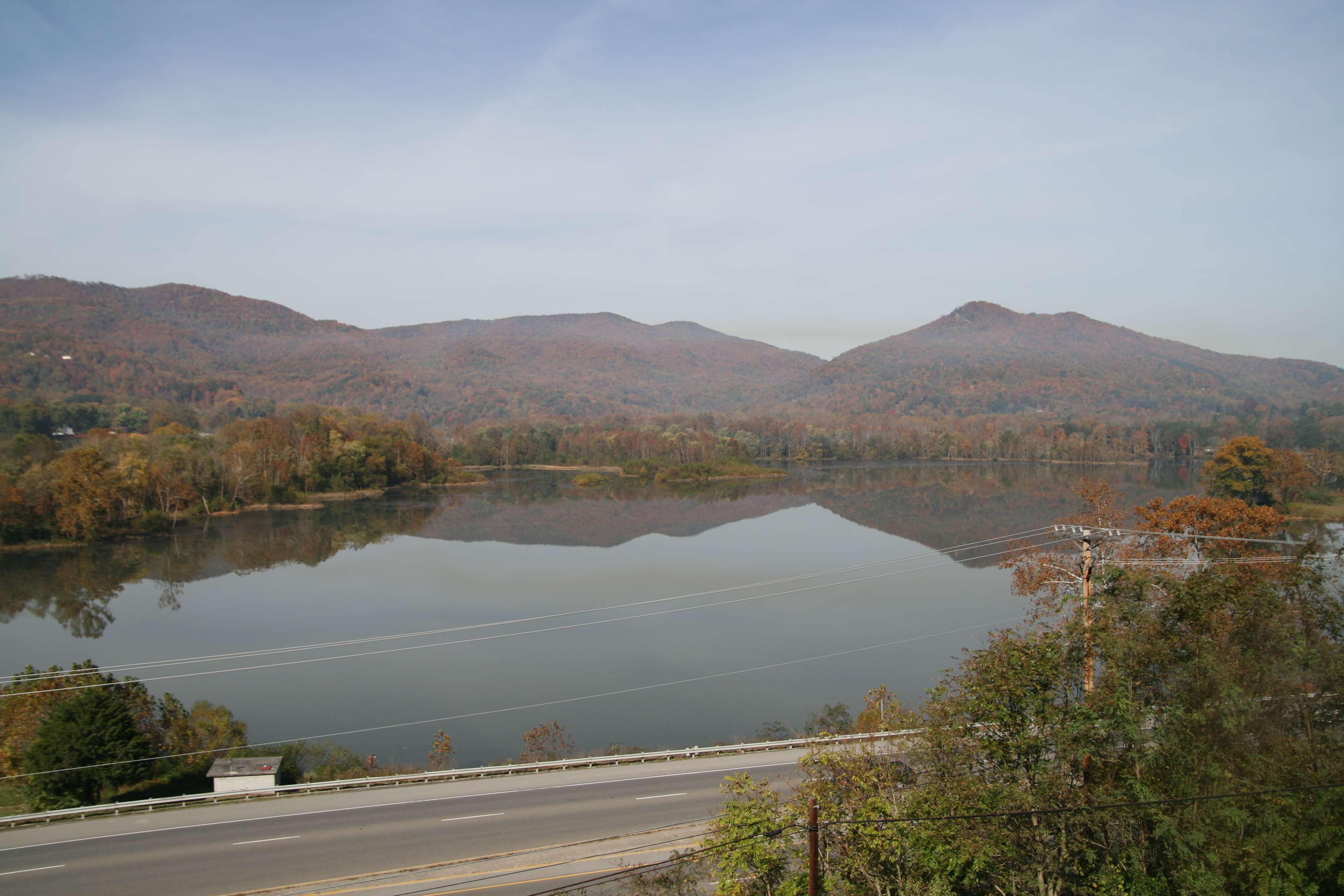 Un lago rodeado de colinas, con una carretera al frente.