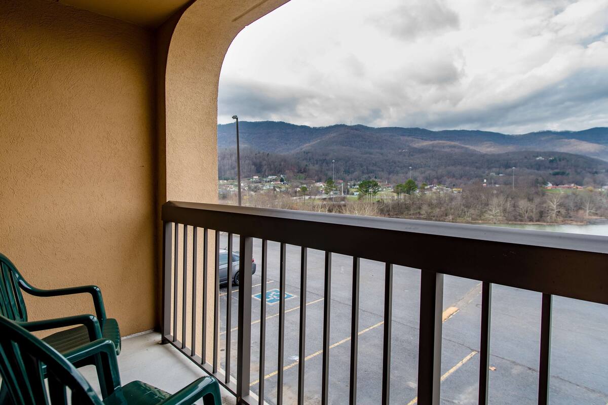 A balcony with a view of a parking lot and mountains.