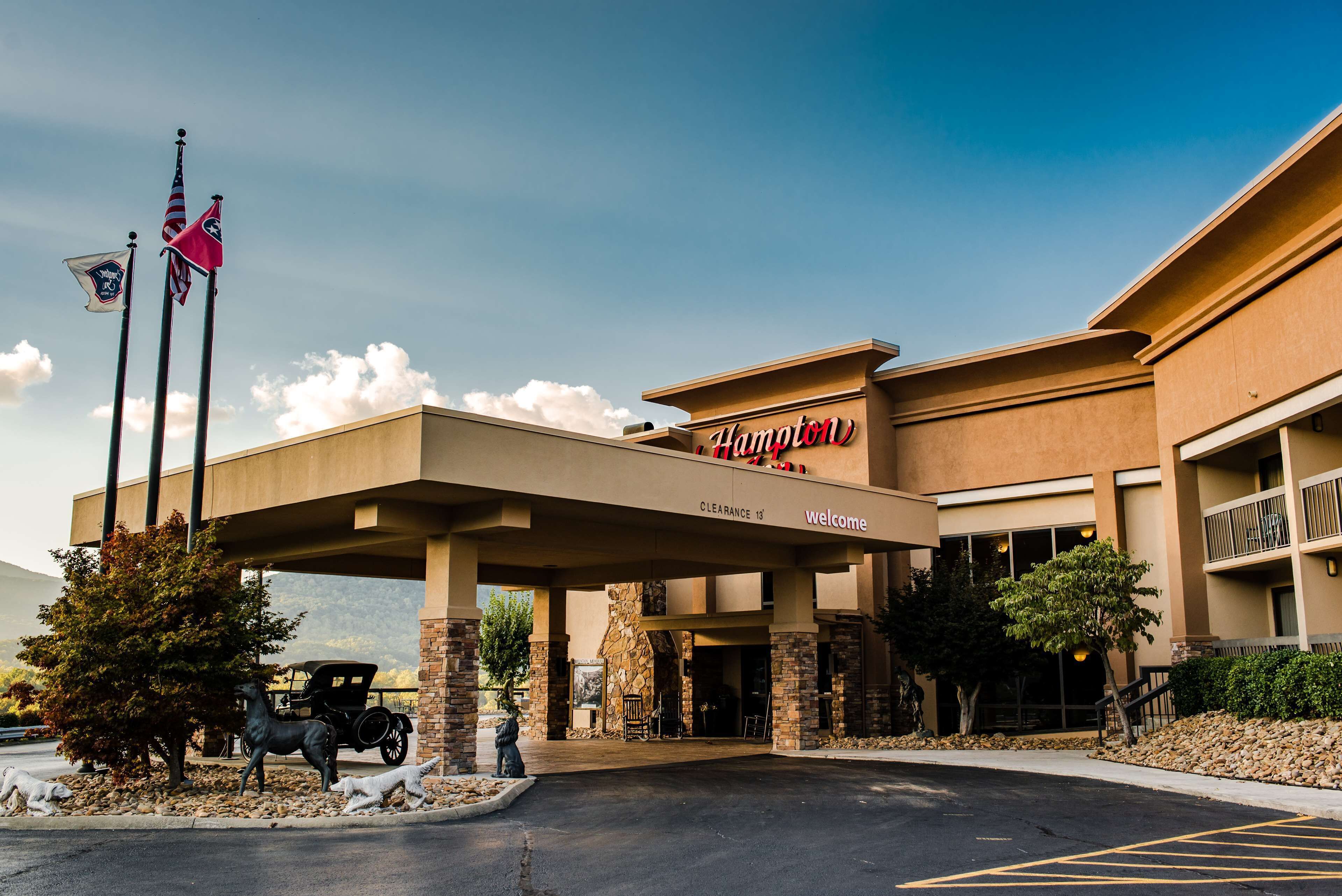 A Hampton Inn with a clear entrance, a covered parking area, and a stone facade.