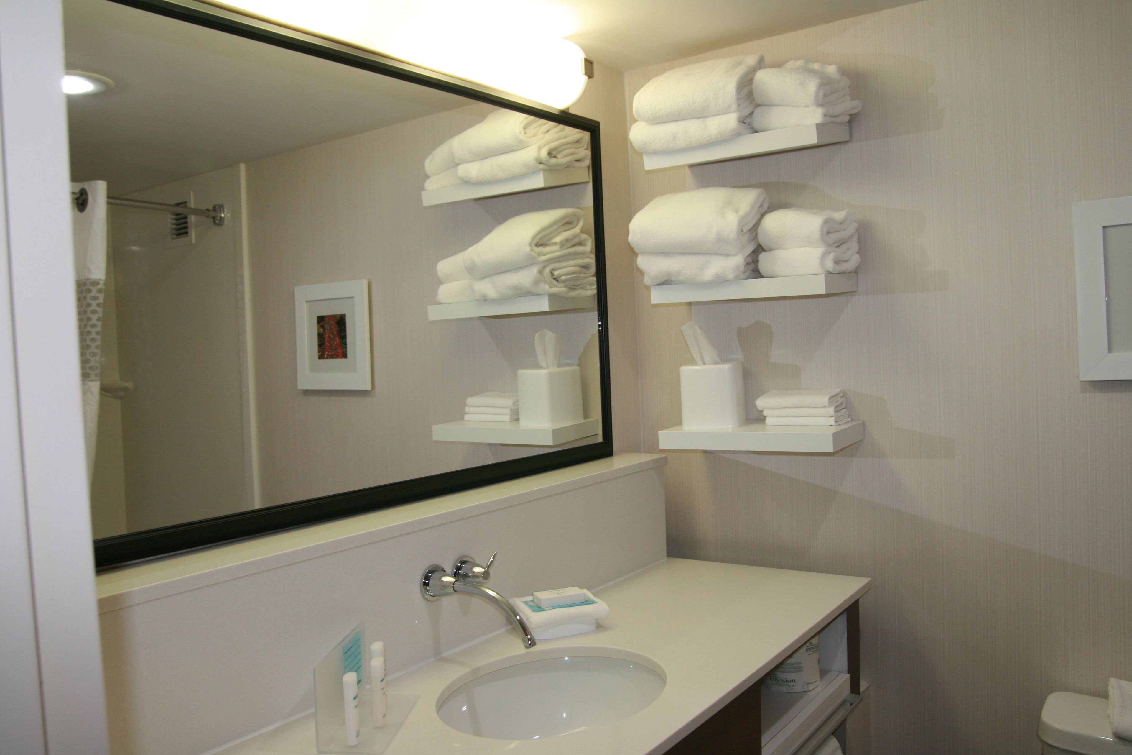 A bathroom with a sink, mirror, towel racks, and a toilet.