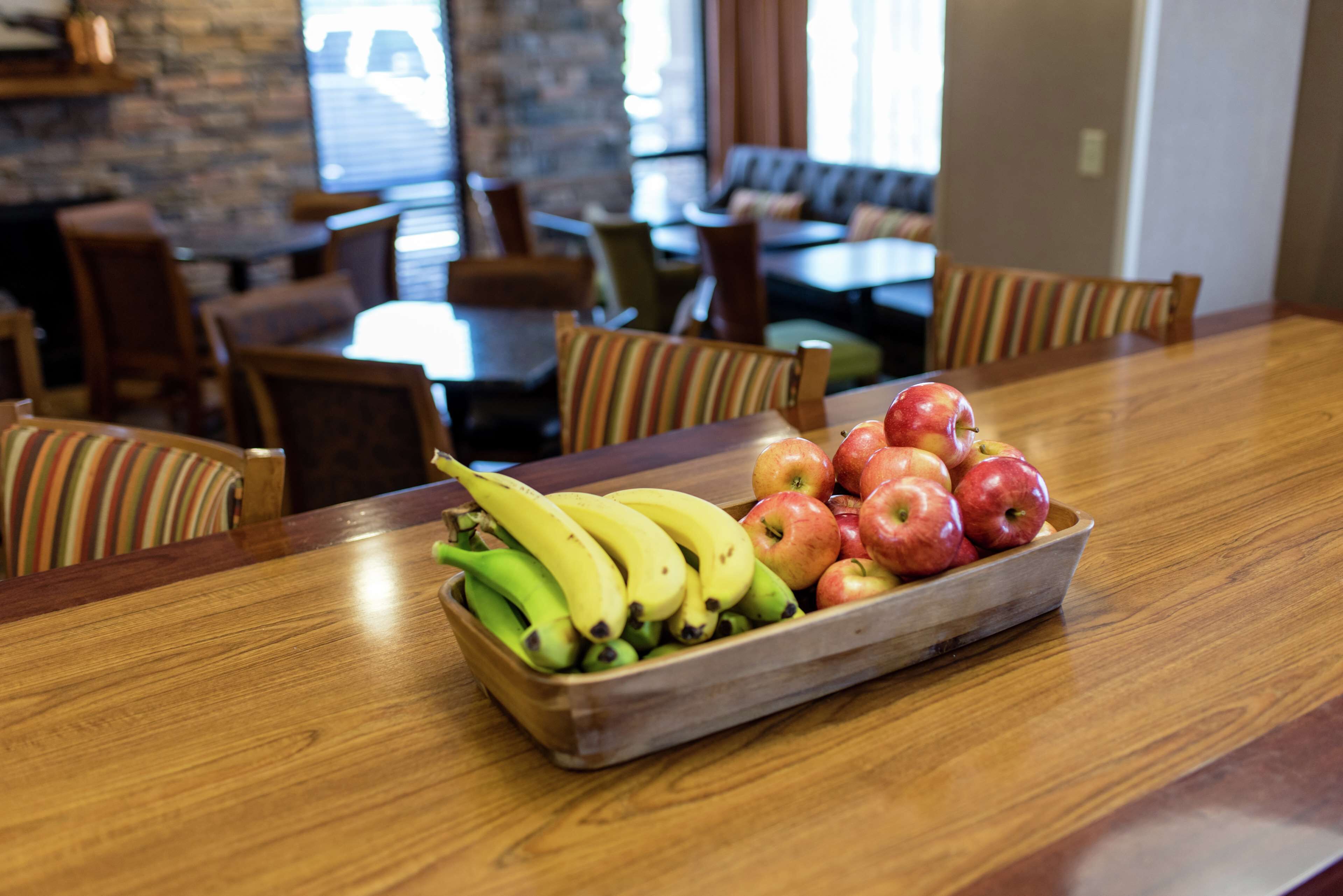 A dining table with a fruit bowl containing bananas and apples.