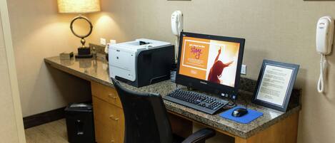 A hotel reception desk with a computer, printer, and telephone.