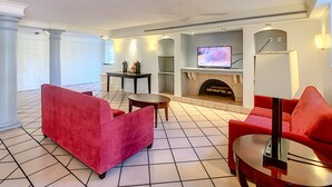 Una sala de estar moderna con chimenea, muebles rojos y televisor.