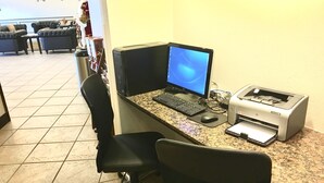 Un espace de travail aménagé à la maison, comprenant un ordinateur de bureau, une imprimante et deux chaises de bureau.