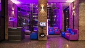 A lobby with a brick wall, a Discount kiosk, and purple lighting. - Travelodge Hotel by Wyndham Montreal Centre (Montreal)