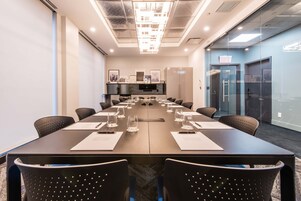 A conference room with a long table, chairs, a television, and a sign that says "SOFT".