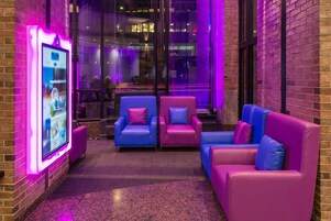 A modern lounge area with seating and a digital kiosk.