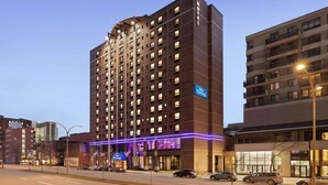 A multi-story hotel with a modern design, featuring a prominent entrance with illuminated signage, a well-lit facade, and a parking area in front. - Travelodge Hotel by Wyndham Montreal Centre (Montreal)