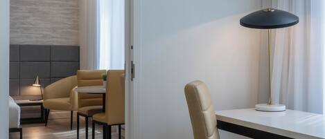 Una habitación de hotel moderna con zona de comedor, sofá y lámpara.