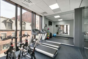 Une salle de sport équipée de tapis de course, de vélos d’appartement et de ballons d’exercice.