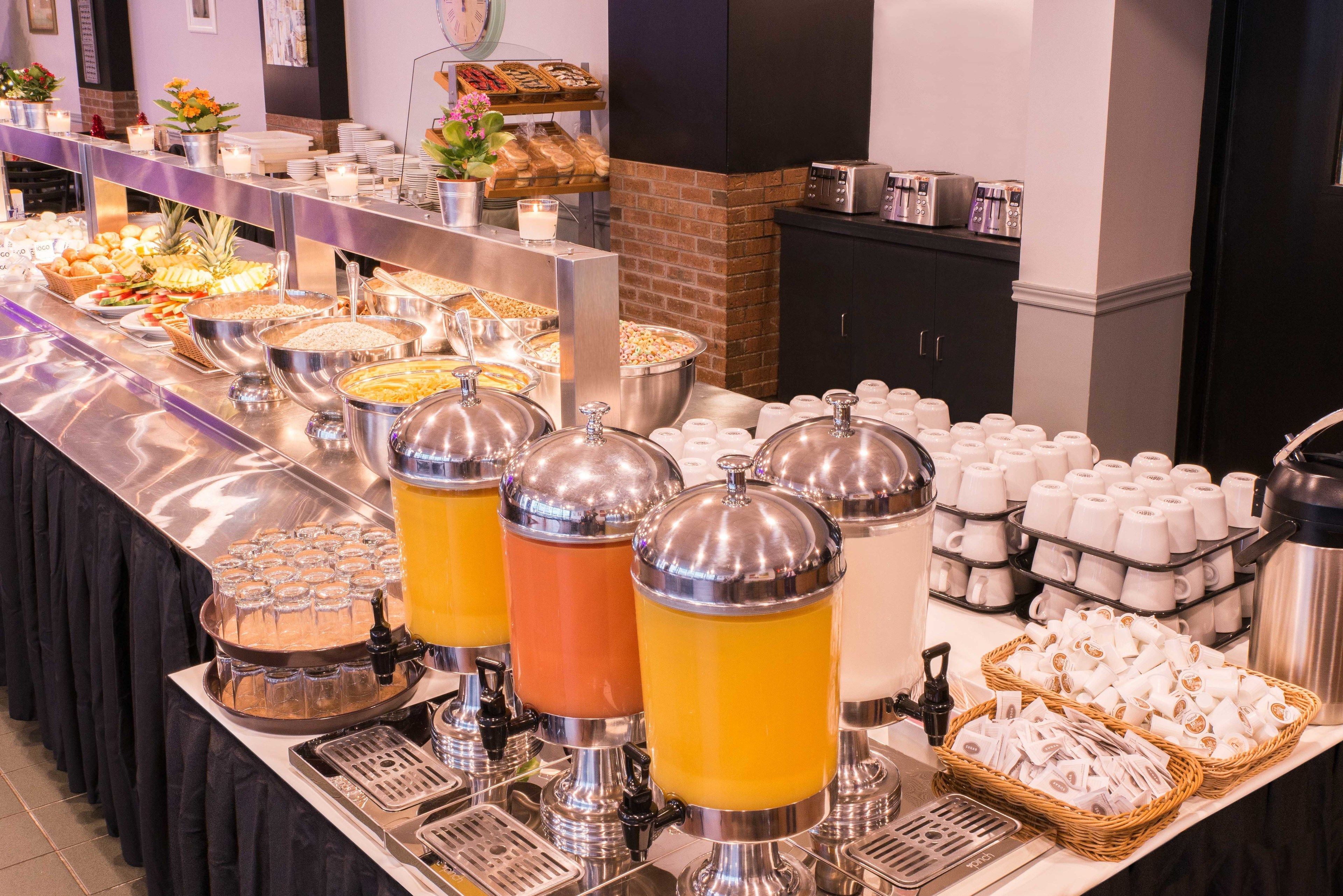 Een buffet met diverse gerechten en dranken, waaronder een koffiehoek en een fruitschaal.
