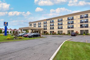 A Comfort Inn hotel with a parking lot, multiple cars, and a clear sky.