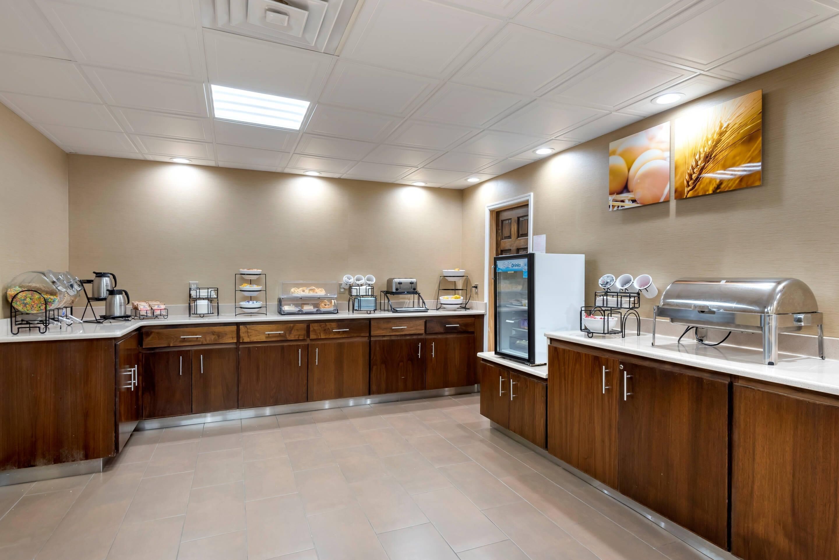 A spacious kitchen with wooden cabinets, a refrigerator, a coffee station, and a buffet area.