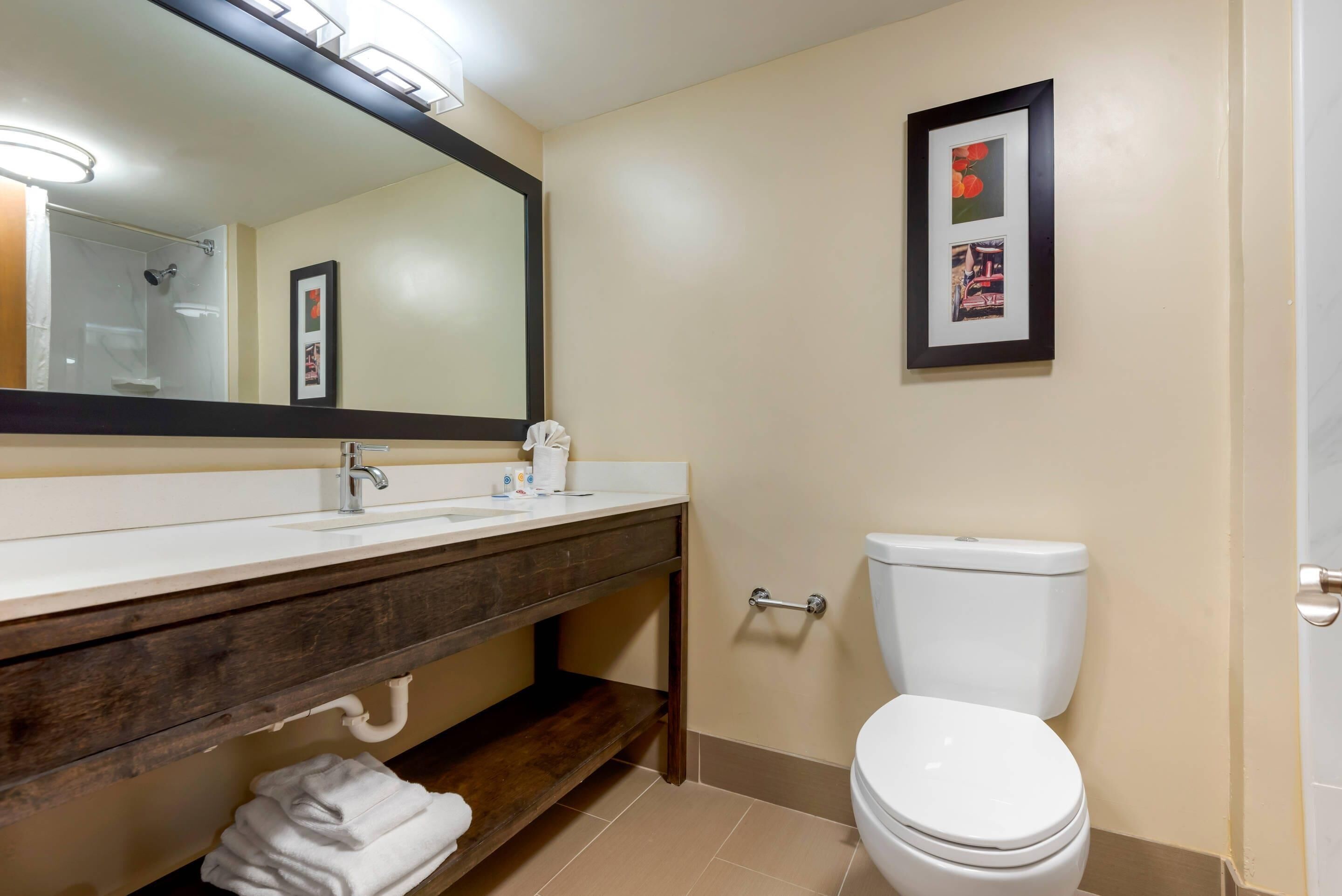 Un baño con lavamanos, espejo y retrete blancos.