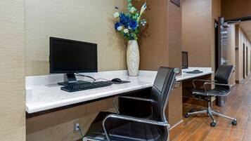 A reception desk with a computer, keyboard, and a vase of flowers.