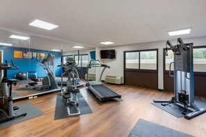 A gym with exercise equipment, a treadmill, and a mirrored wall.