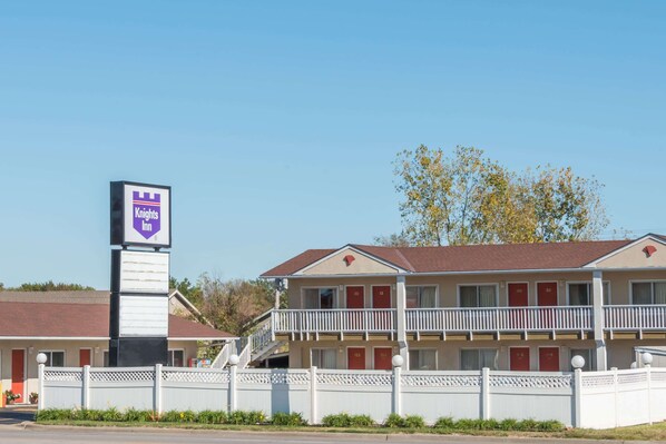 A Knights Inn with a two-story building, a white fence, and a clear blue sky.