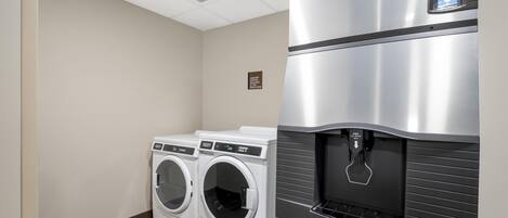 A laundry room with two front-loading washers and a stainless steel refrigerator with a water dispenser.