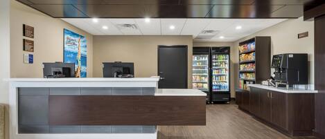 A reception area with a counter, a refrigerator, and a coffee machine.