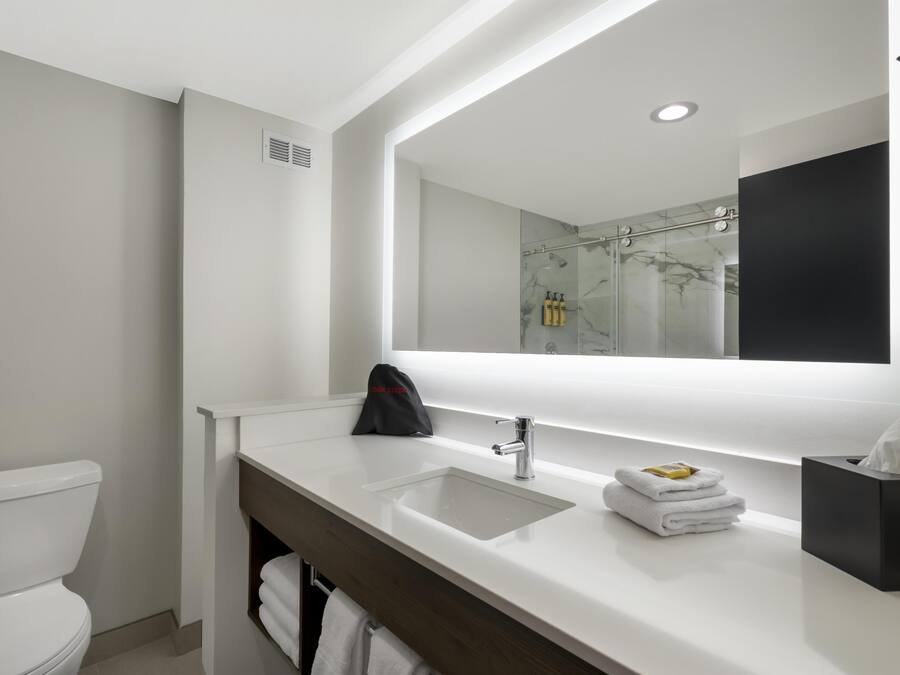 A modern bathroom with a white sink, a large mirror, and a glass shower enclosure.