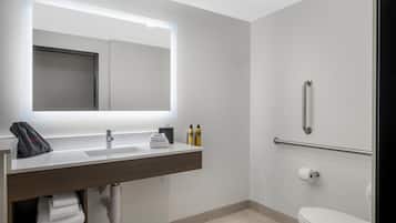 Un baño moderno con un espejo grande, un lavabo, un inodoro y una zona de ducha.