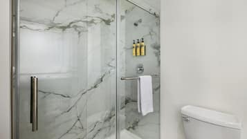 A bathroom with a glass-enclosed shower, a toilet, and a towel rack with a towel.