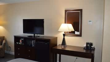 A hotel room with a bed, a television on a dresser, a lamp, a coffee maker, and a microwave.