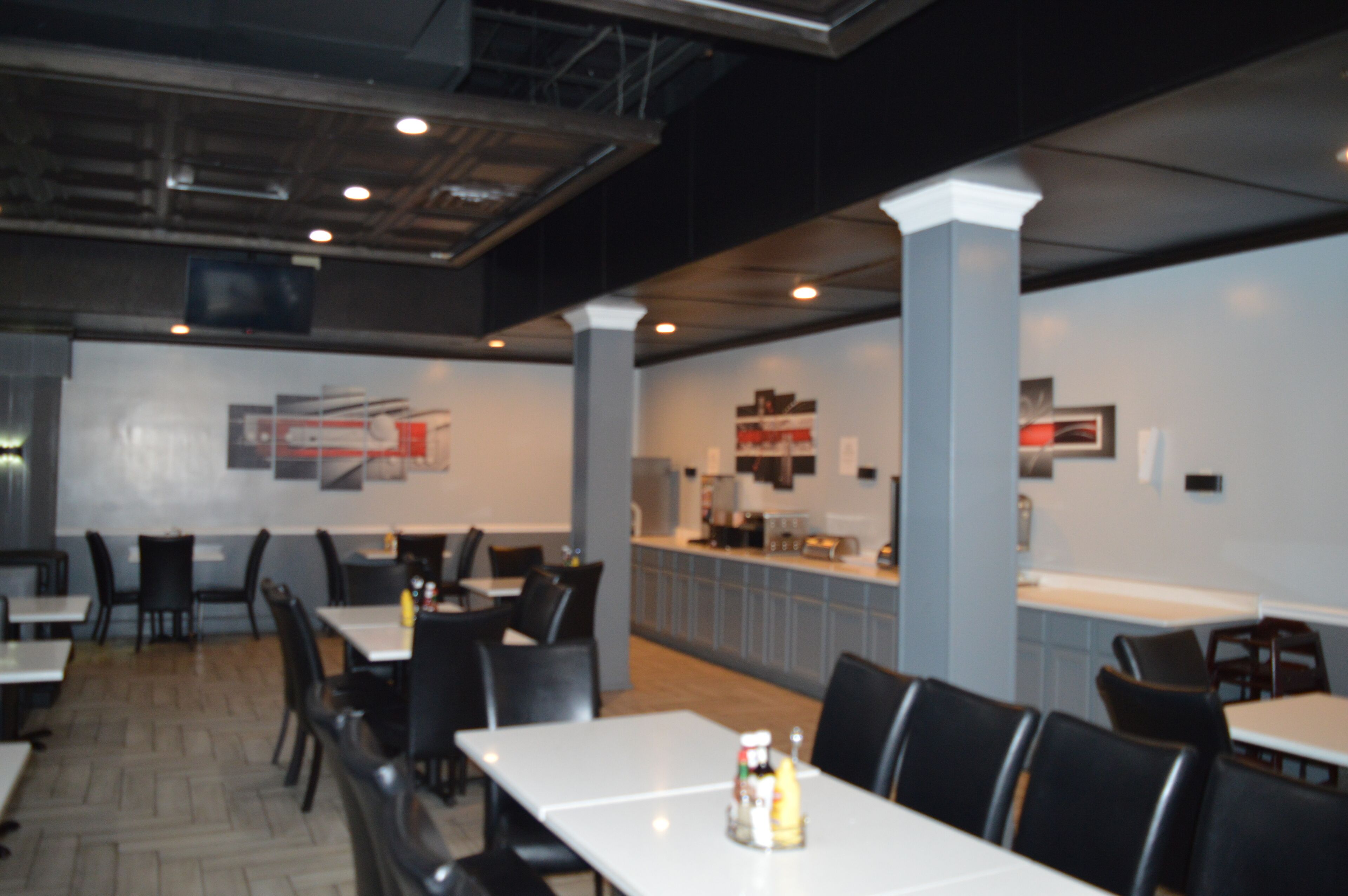 Un restaurant moderne avec un intérieur caractérisé par de hauts plafonds, des conduits apparents et un mélange de tables et de banquettes.