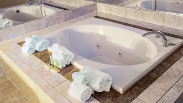 A modern bathroom with a large bathtub, two sinks, and a mirror.