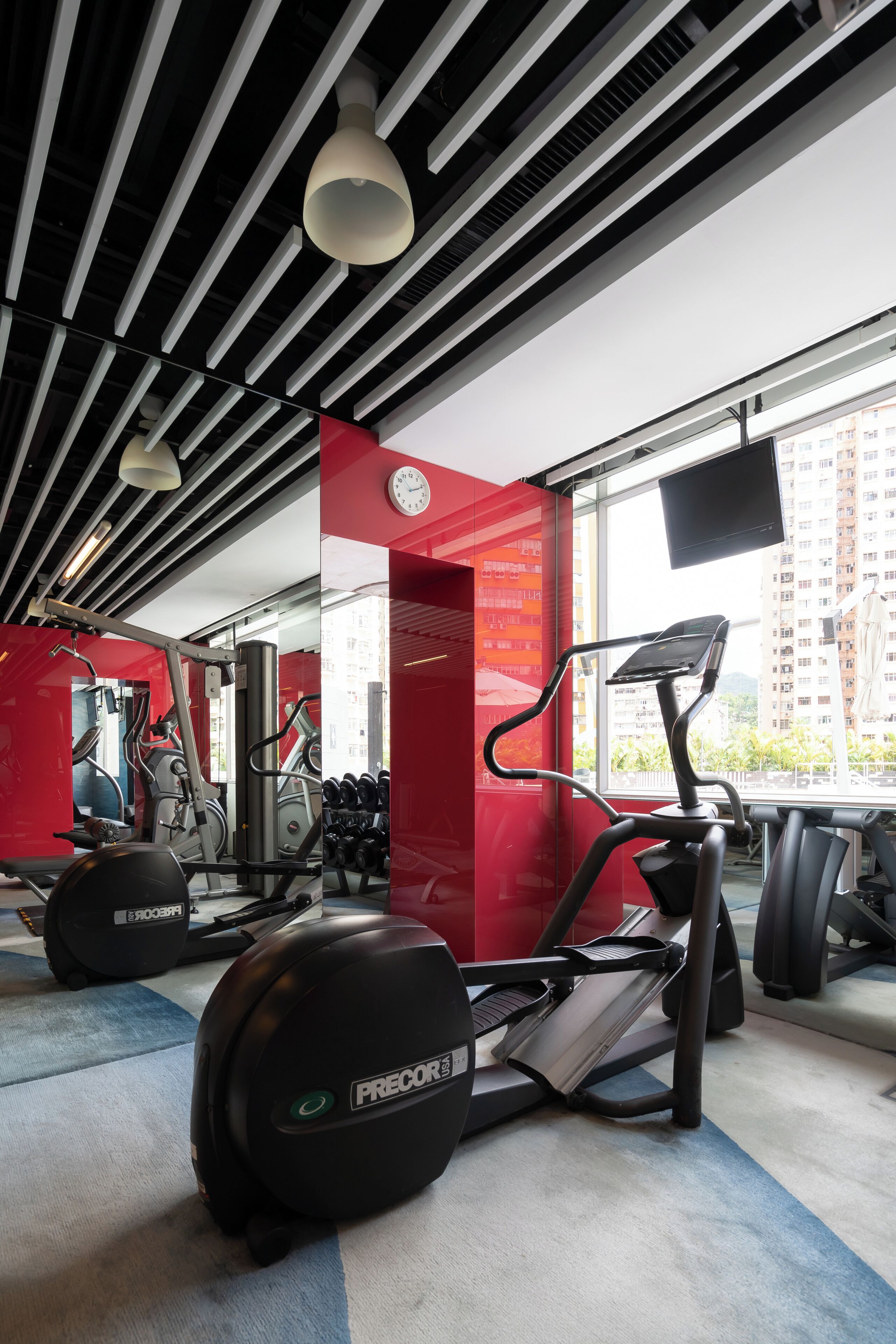 A gym with treadmills, weights, and a large window.