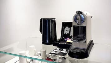 Una máquina de café sobre una mesa de vidrio con una bandeja de tazas blancas y un recipiente negro.