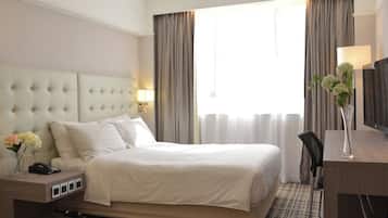 A hotel room with a large bed, bedside tables, a desk, and a chair.