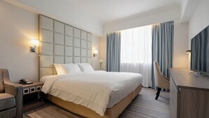 A hotel room with a large bed, a desk, a chair, a TV, and a nightstand with a phone. - Panda Hotel (Tsuen Wan)