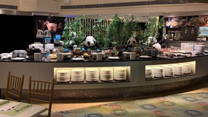 A buffet area with a panda mascot, neatly arranged plates, and a variety of dishes. - Panda Hotel (Tsuen Wan)