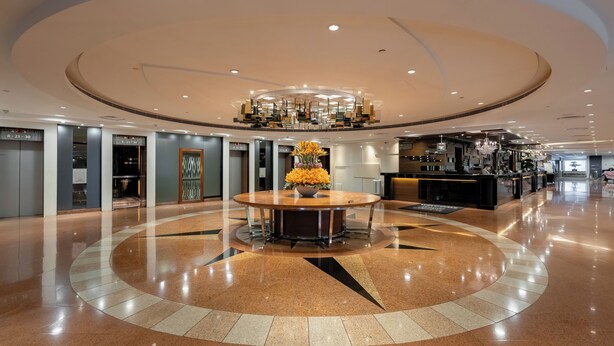 A spacious lobby with a central round table, a reception desk, and a modern chandelier. - Panda Hotel (Tsuen Wan)