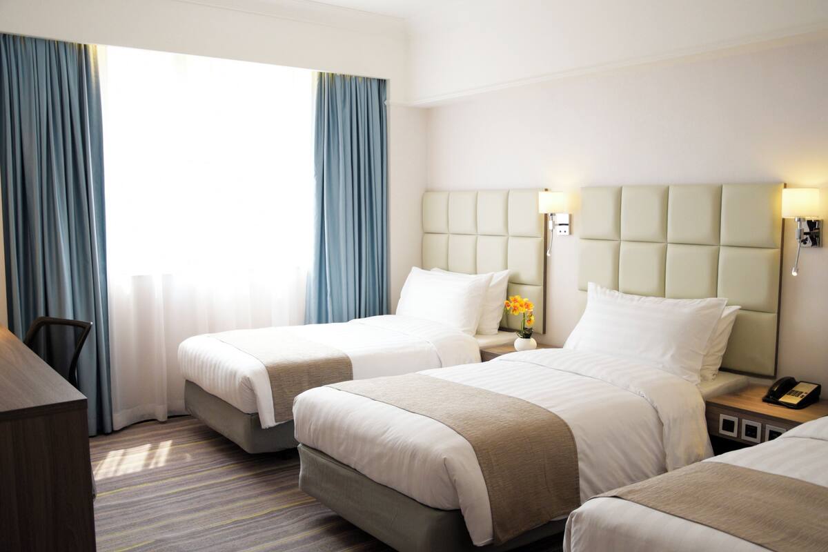 A hotel room with two beds, a desk, and a chair.