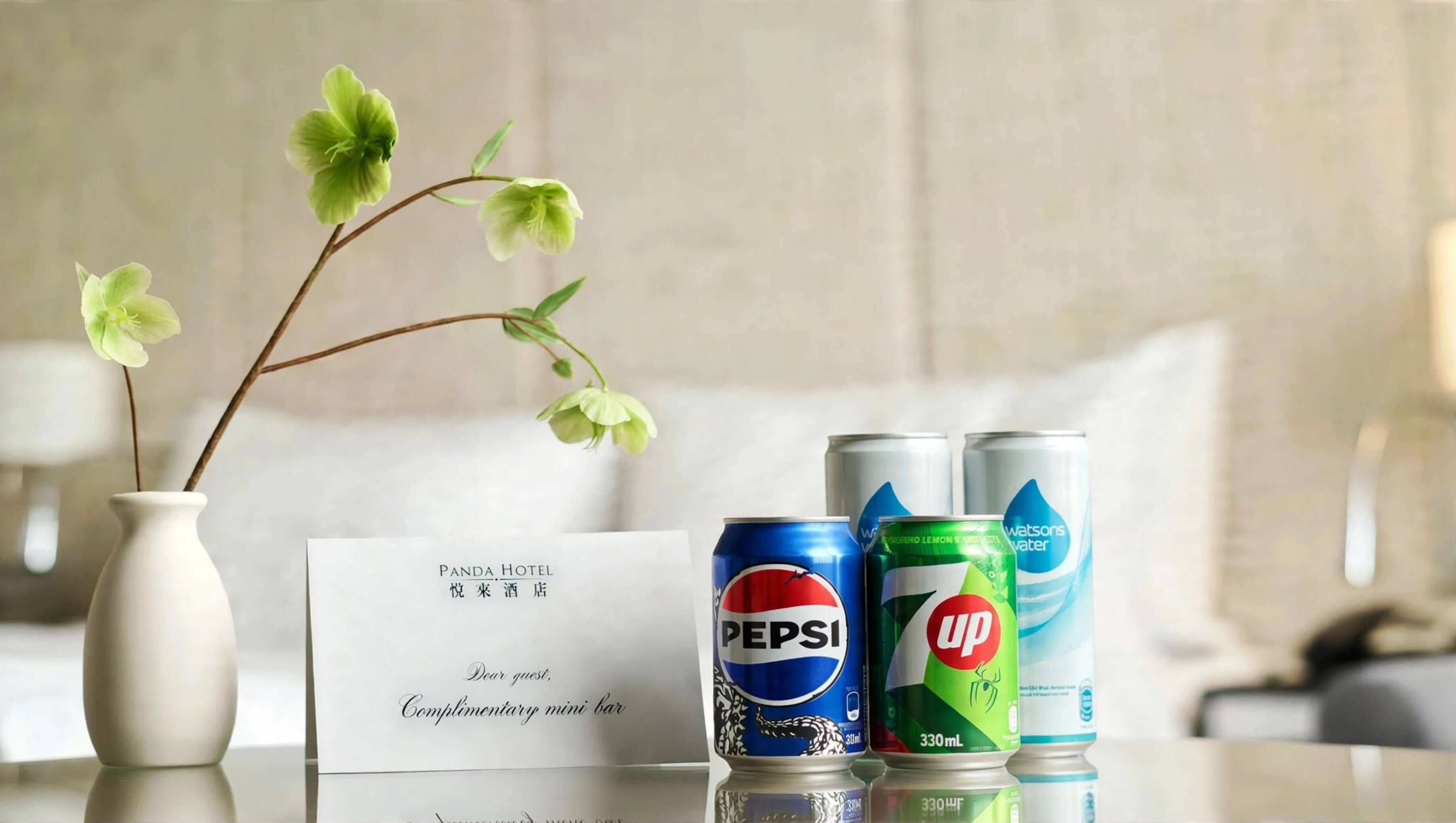 Ett hotellrum med en vit vas med blommor, en minibar som ingår i priset och två burkar med dryck.