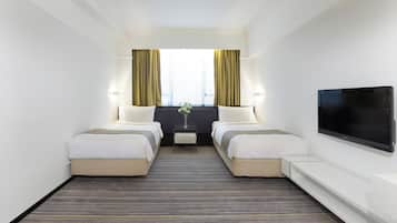 Quarto de hotel com duas camas, televisão de tela plana, janela com cortinas e uma mesinha com um vaso.