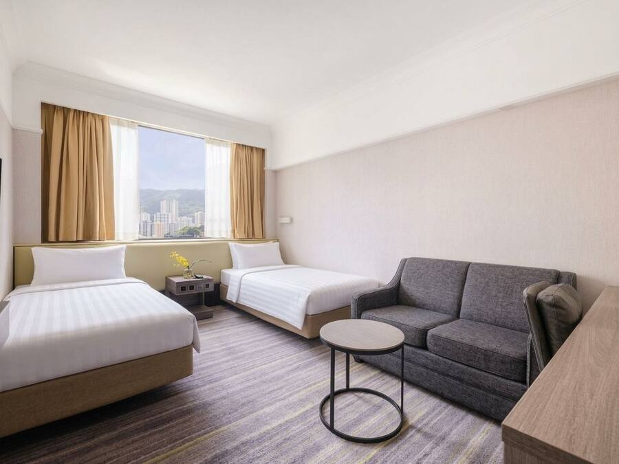 Habitación de hotel con dos camas, un sofá, una mesita y un televisor.