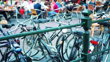 Bicycles parked in an outdoor seating area with tables and chairs.