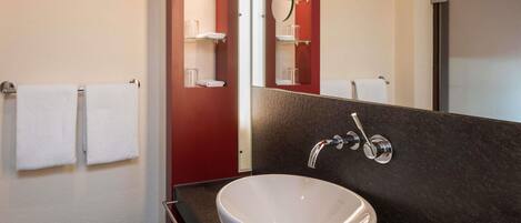 Une salle de bain avec un lavabo blanc, un miroir et deux serviettes posées sur un porte-serviettes.