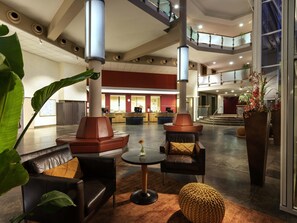 A spacious lobby with leather seating, a reception desk, and a staircase leading to upper levels. - Mövenpick Hotel Münster am Aasee (Münster)