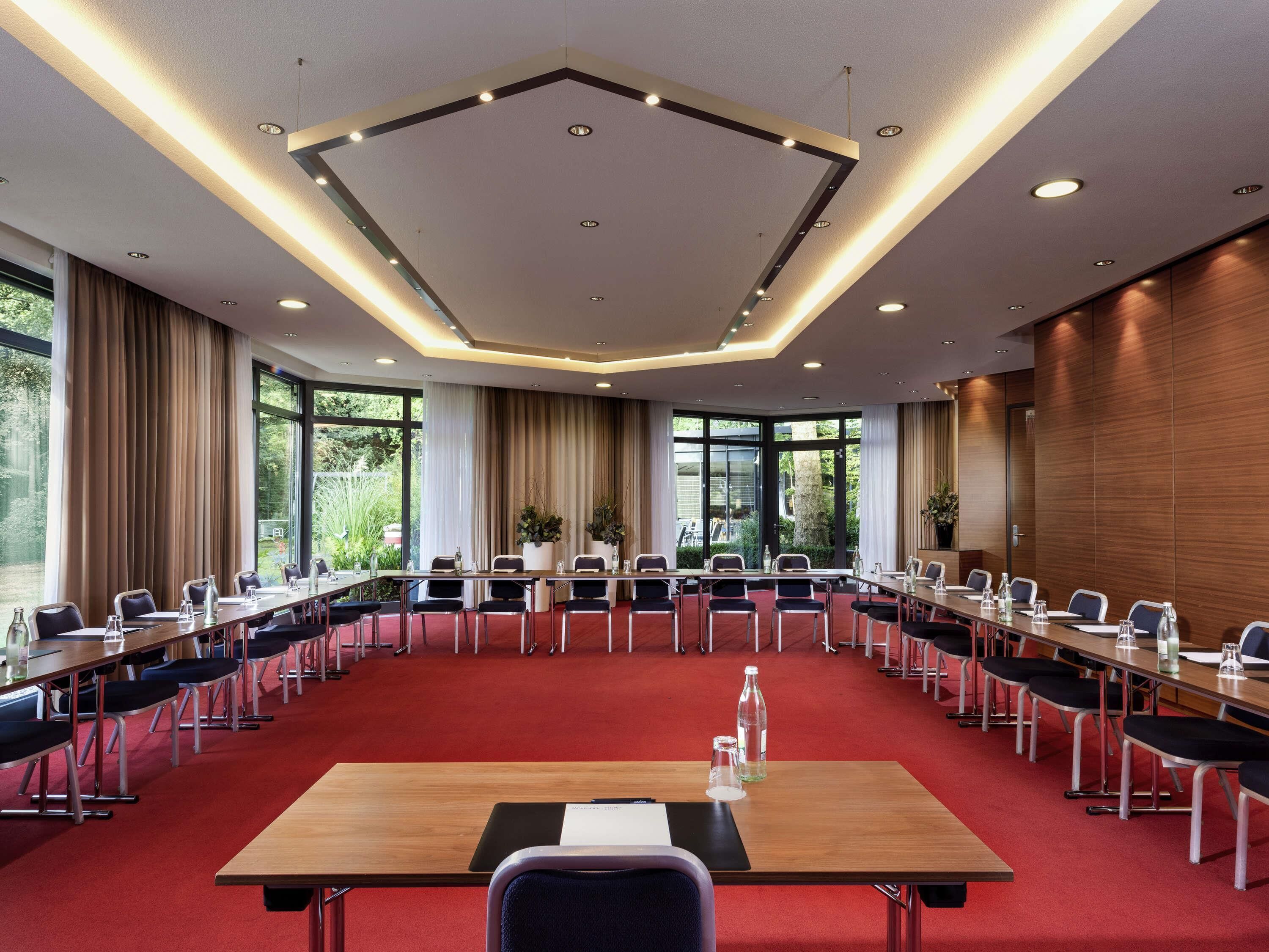 A conference room with a long table, multiple chairs, and a red carpet.
