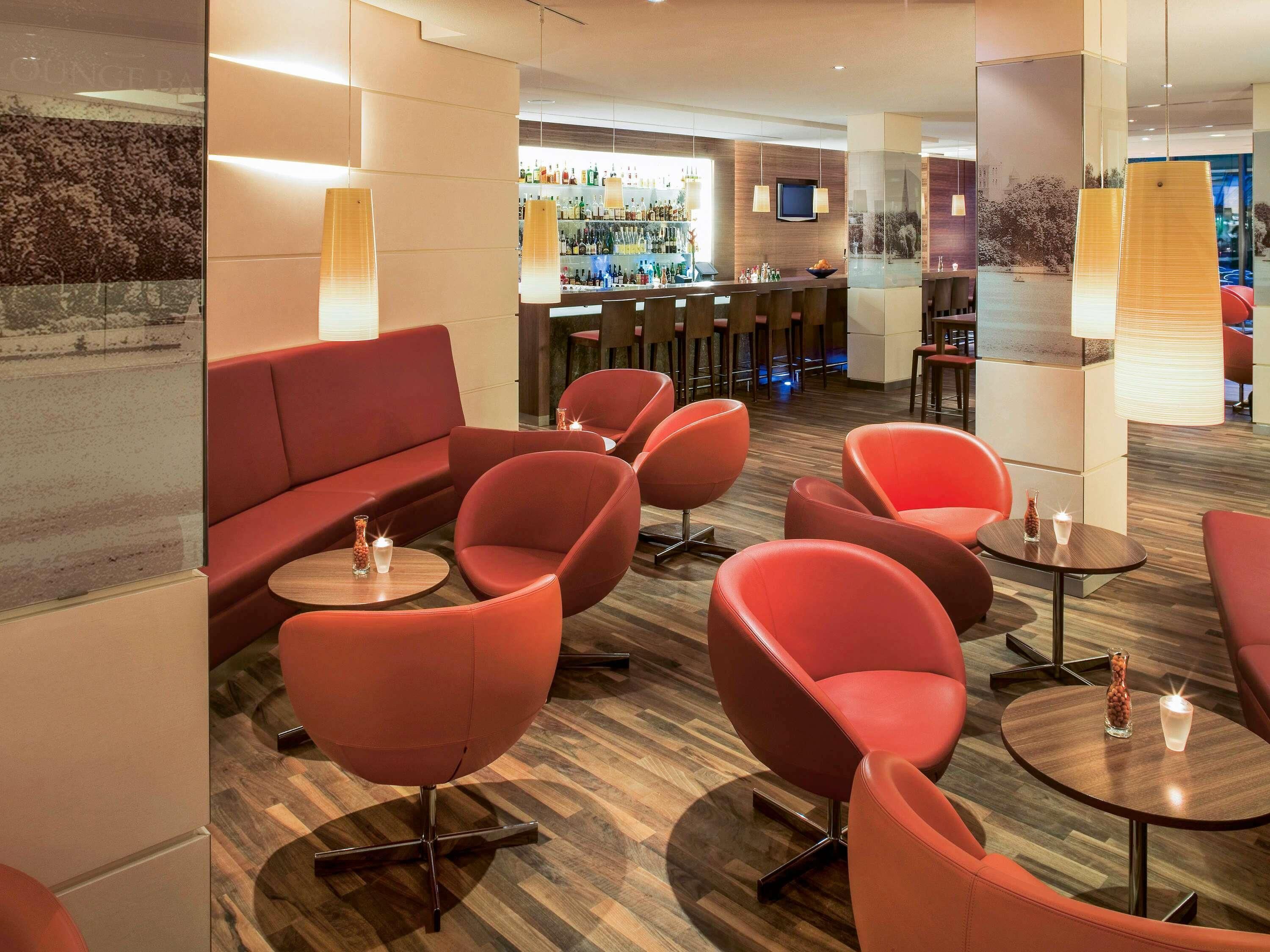 Een moderne lounge met rode zitplaatsen, een bar op de achtergrond en een houten vloer.