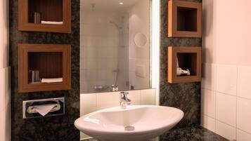 A bathroom with a white sink, wooden medicine cabinets, a mirror, and a shower area.