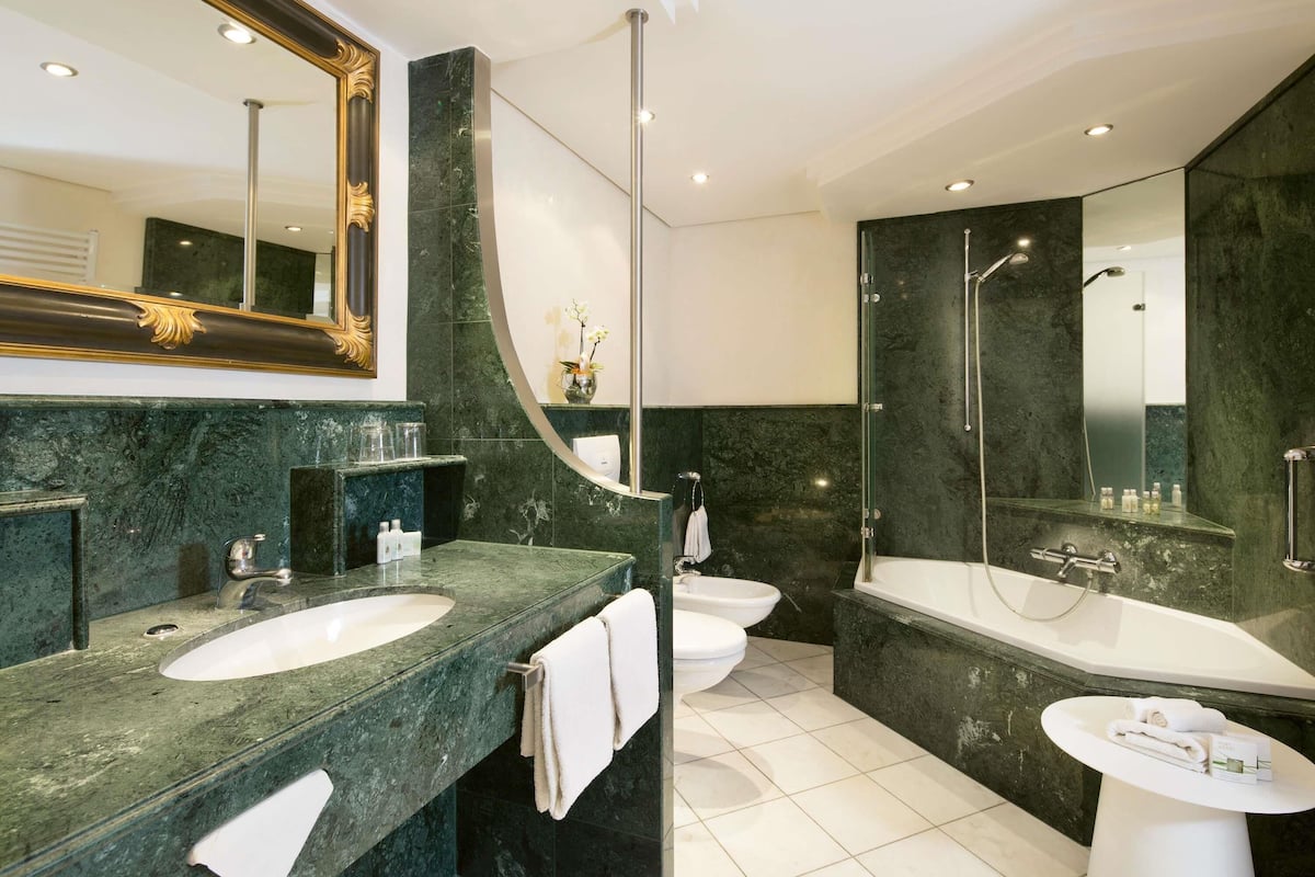 Ein modernes Badezimmer mit großem Spiegel, einer Badewanne, einer Dusche und einem Waschbecken.