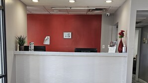 A reception desk with a red wall, a black doormat, and a sign that reads "BAYMONT BY WYNDHAM". - Baymont by Wyndham Covington (Covington)